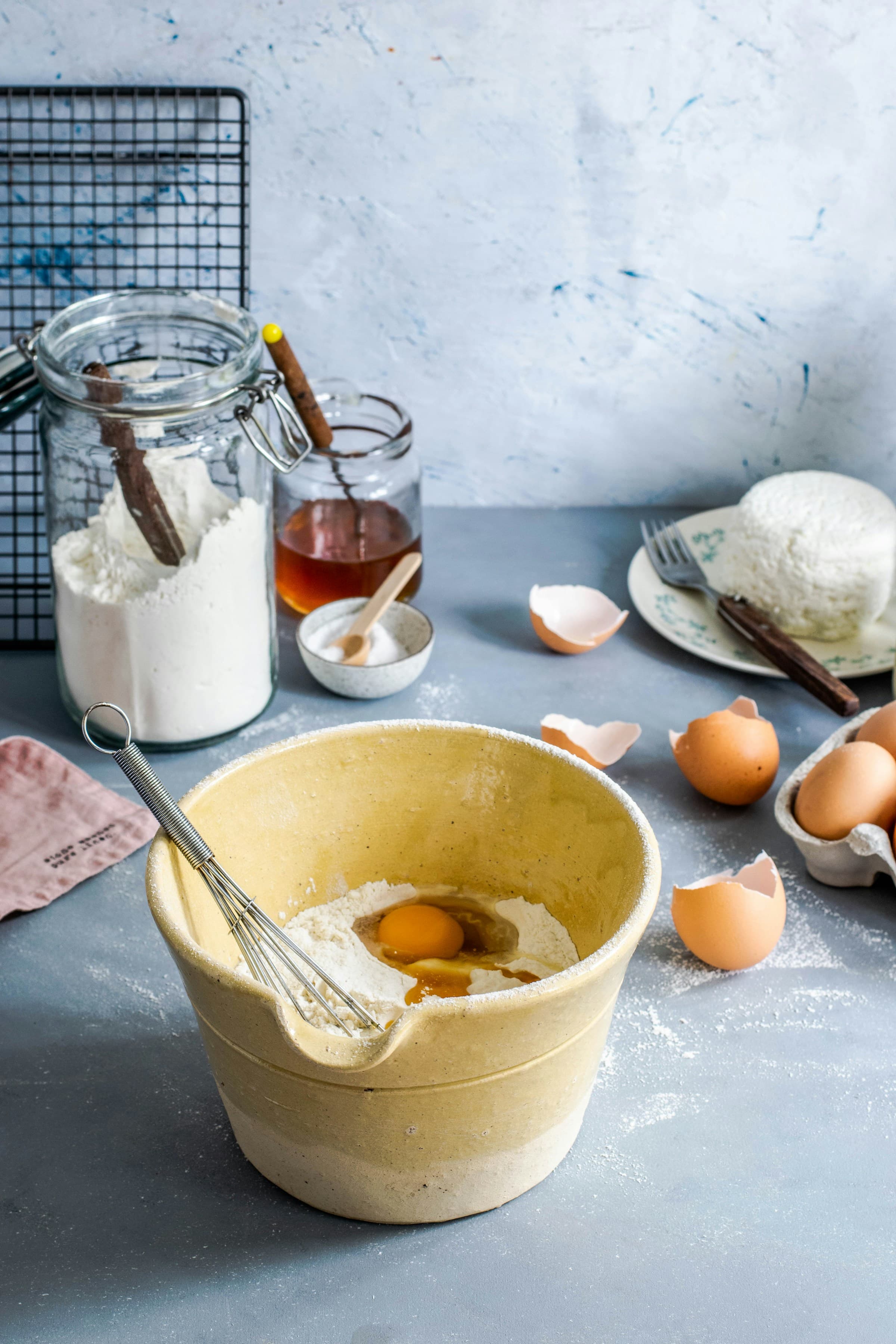 Baking scene with mixing bowl, eggs, flour jar, and honey